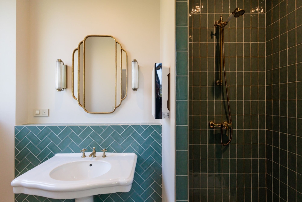 Salle de bain chambre d'hôtel Essentielle, carrelage vert chevron et miroir Art Déco doré — La Villa Kara, près de Valence