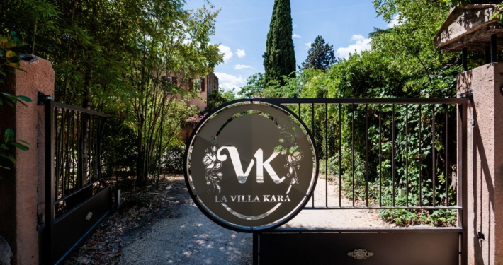 Portail en fer forgé avec médaillon logo VK, entrée du domaine de La Villa Kara — Drôme