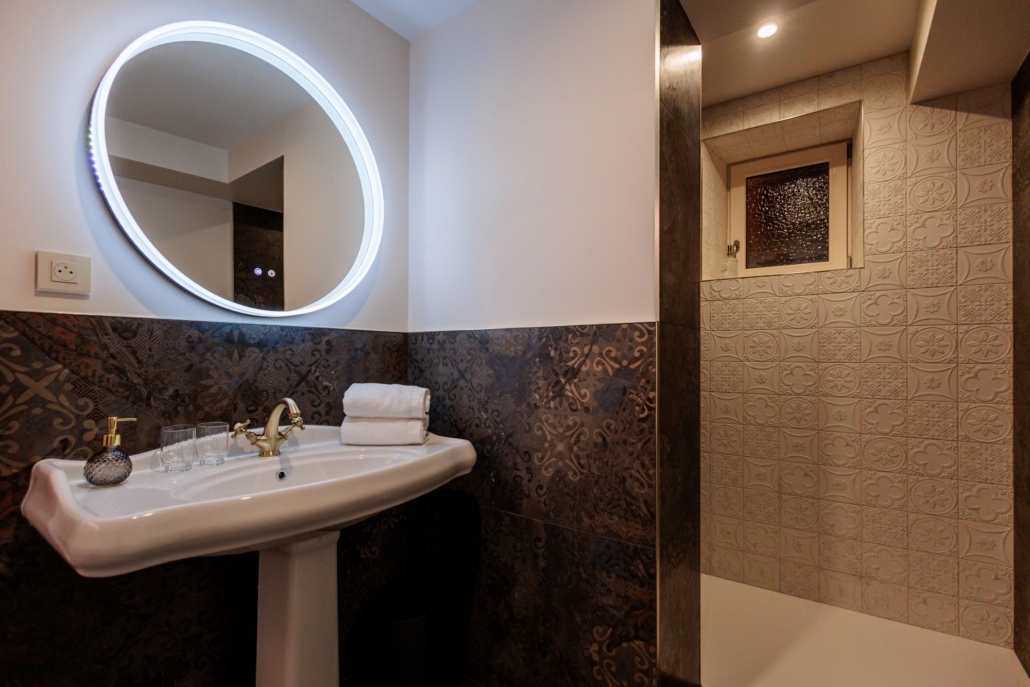 Vasque sur pied et miroir rond lumineux, salle de bain de la Suite Kara avec douche— La Villa Kara, proche Valence