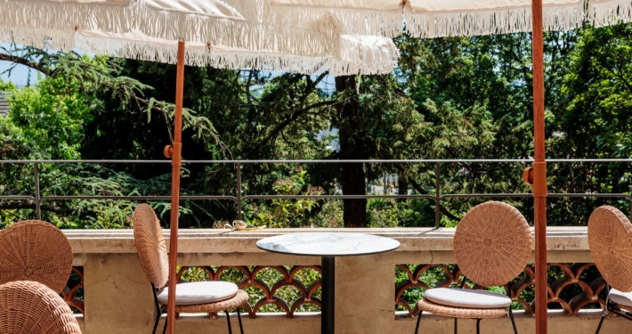 Terrasse ombragée par des parasols à franges, table en marbre et chaises en rotin avec vue sur le parc — La Villa Kara, Romans-sur-Isère